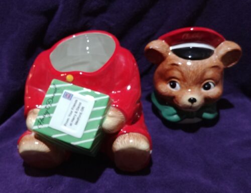 A red ceramic dog mug sitting next to a brown bear.