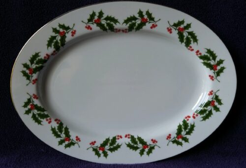 A white plate with red and green holly leaves.