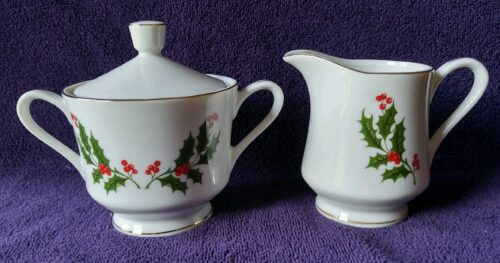 A white sugar bowl and creamer set with red holly leaves.