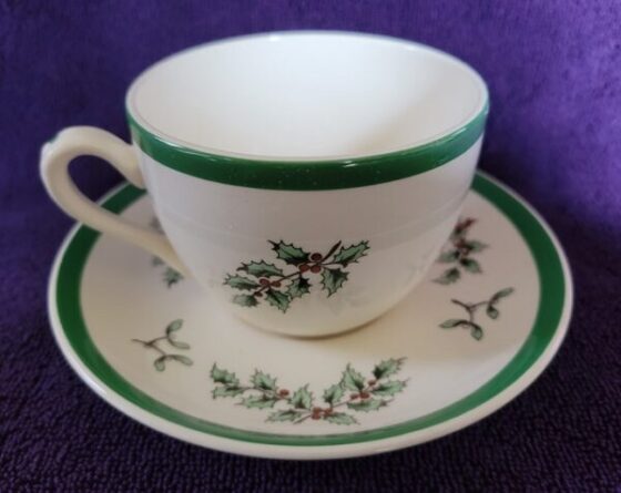 A cup and saucer with green trim on purple background.